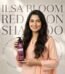 Smiling woman holding Ilsa Bloom Red Onion Shampoo against a branded background with red onion illustrations.